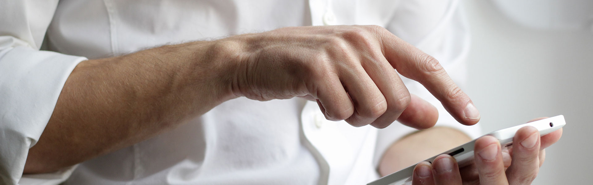 Mann tippt auf Handy: Wir sind auch mobil für Sie erreichbar.